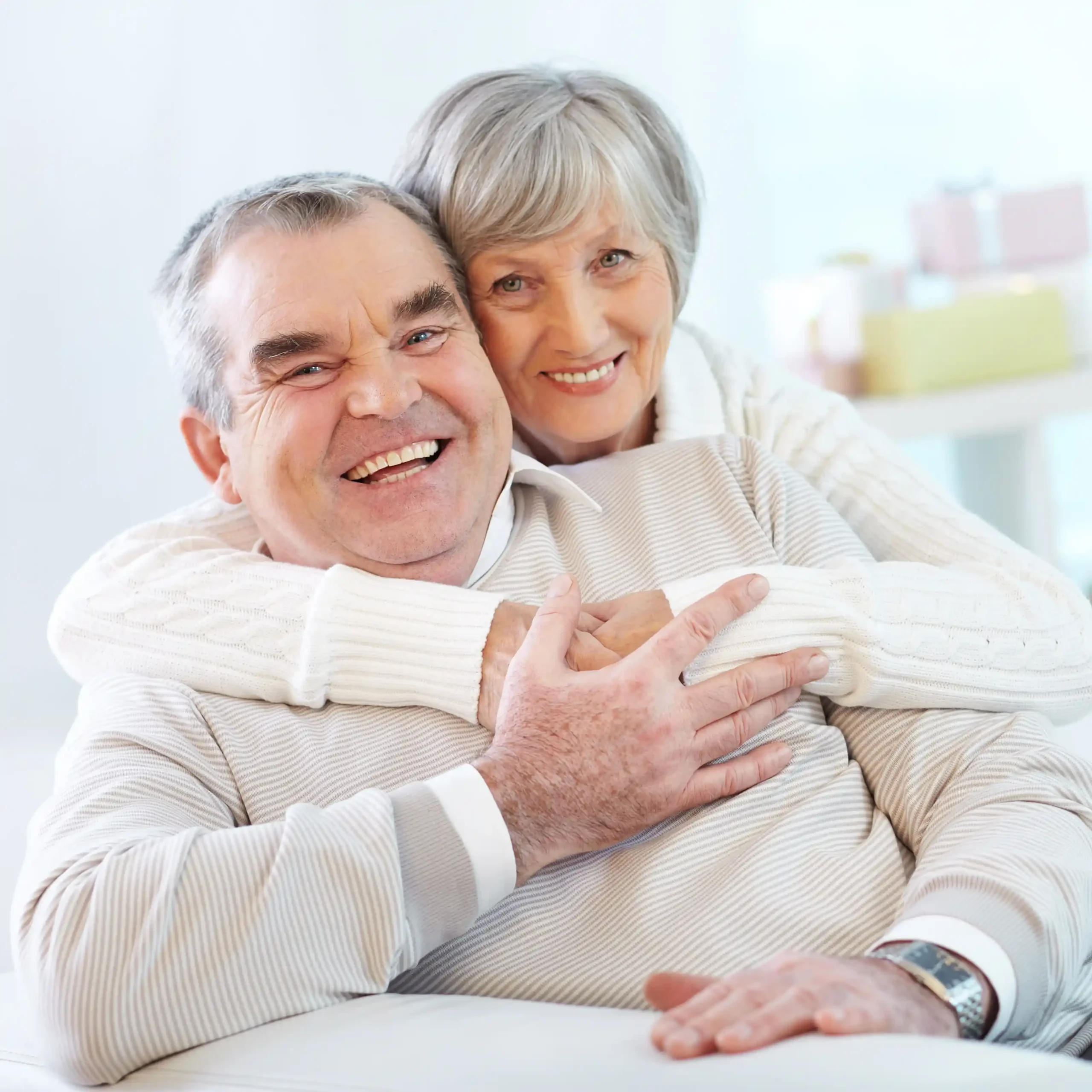 Senior couple hugging at home with dental implants